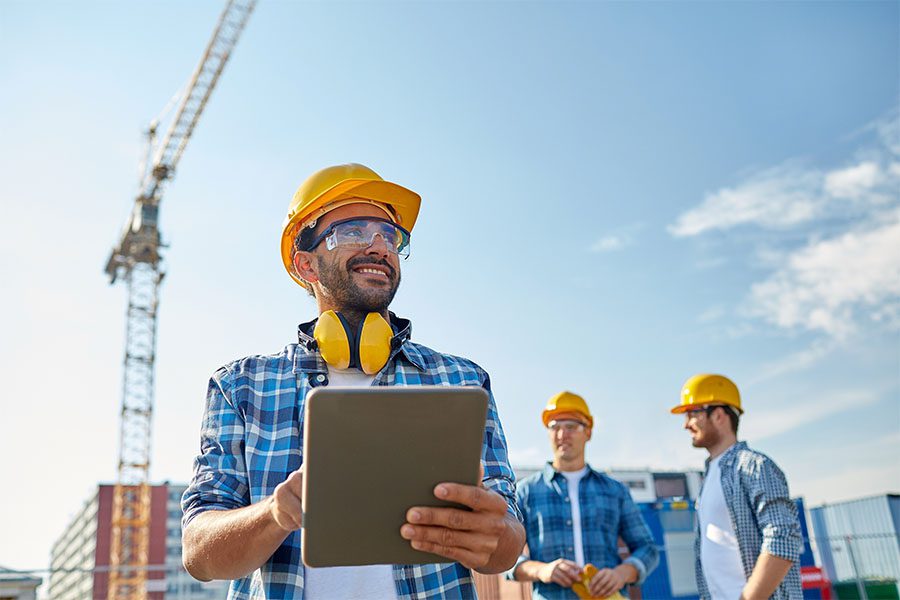 Specialized Business Insurance - Closeup Portrait of a Smiling Contractor Holding a Tablet While Standing on a Construction Jobsite